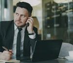 Home Focused businessman speaking on phone at office desk.